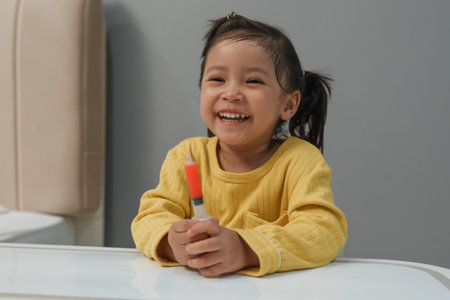 happy toddler girl holding syrup medicine with syringeの写真素材
