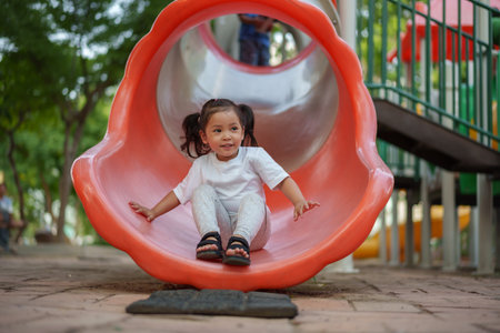 happy toddler baby girl sliding and playing at the playgroundの写真素材