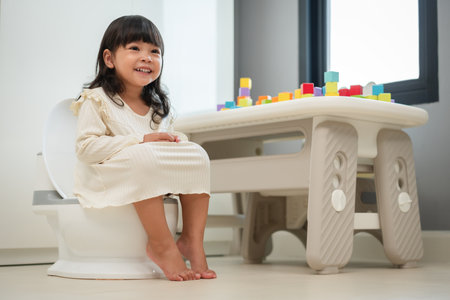 happy toddler girl learning sit on a toilet wc seat at home. child being potty trainedの写真素材