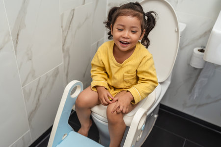 happy toddler girl is sitting on the toilet at home. potty training and learningの写真素材