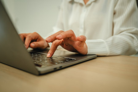 hands typing on a laptop keyboard at home office