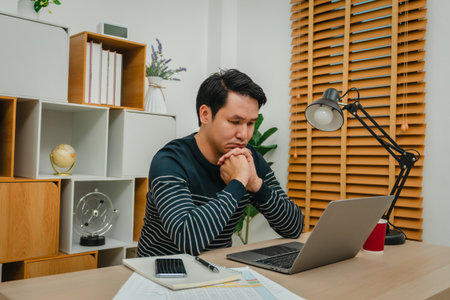 worried young man working with laptop computer at home office