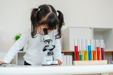 toddler girl scientist looking through a microscope. learning science