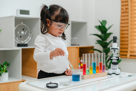 toddler girl scientist study using pipette dropping liquid with test tube and beaker. learning...