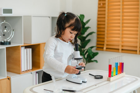 toddler girl scientist placing microscope slides with specimen. learning science at homeの写真素材