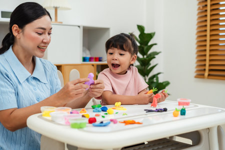 toddler girl with her mother sculpting from plasticine at homeの写真素材