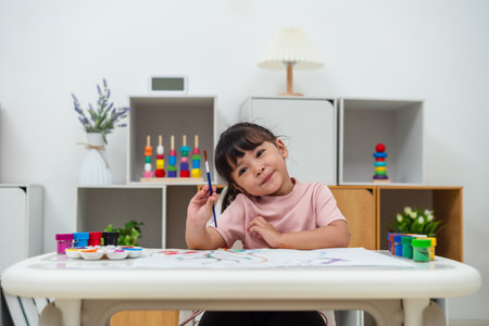 happy toddler girl painting watercolor in a paper at homeの写真素材