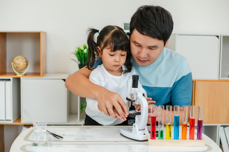 father and toddler girl scientist placing microscope slides with specimen. learning science at home