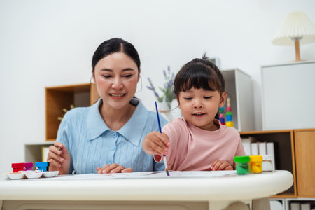 happy mother and toddler girl painting watercolor in a paper at homeの写真素材