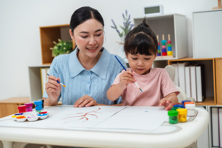 happy mother and toddler girl painting watercolor in a paper at homeの写真素材