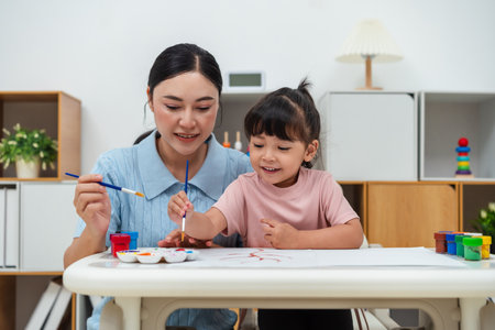 happy mother and toddler girl painting watercolor in a paper at homeの写真素材