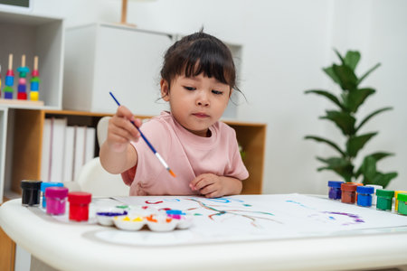 happy toddler girl painting watercolor in a paper at homeの写真素材