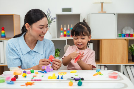 toddler girl with her mother sculpting from plasticine at homeの写真素材
