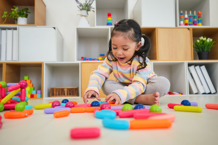 happy toddler girl playing colorful magnetic construction toyの写真素材