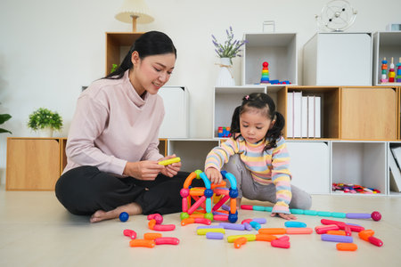 happy toddler girl and mother playing colorful magnetic construction toy at homeの写真素材