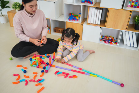 happy toddler girl and mother playing colorful magnetic construction toy at homeの写真素材