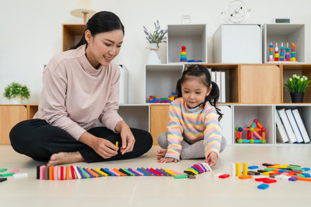 happy toddler girl and mother playing colorful wooden block toy or domino game togetherの写真素材