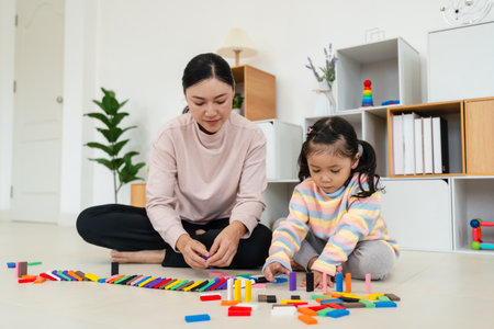 happy toddler girl and mother playing colorful wooden block toy or domino game togetherの写真素材