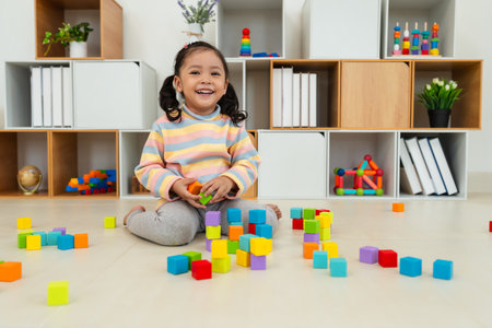 happy toddler girl playing block toy to stacks building cubes at homeの写真素材