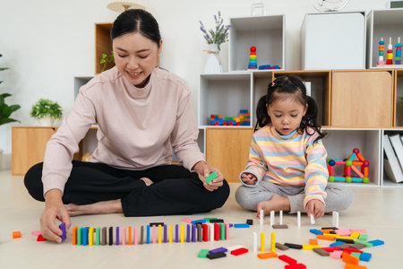 happy toddler girl and mother playing colorful wooden block toy or domino game togetherの写真素材
