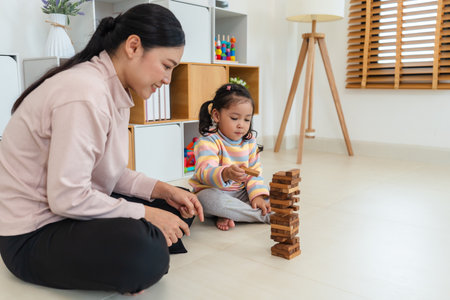 happy toddler girl with mother playing wooden block toy togetherの写真素材