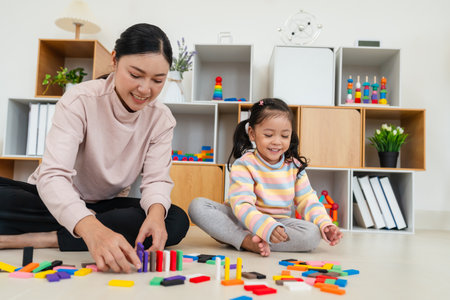 happy toddler girl and mother playing colorful wooden block toy together