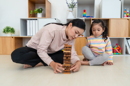 happy toddler girl with mother playing wooden block toy togetherの写真素材