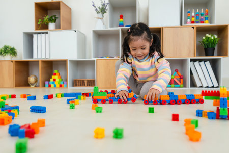 happy toddler girl playing building blocks or plastic bricks toy at homeの写真素材