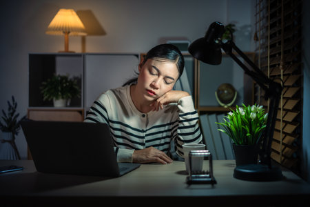 sleepy woman working with laptop at a nightの写真素材