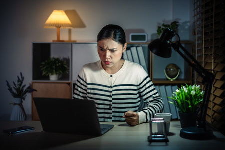 angry woman working with laptop at a nightの写真素材