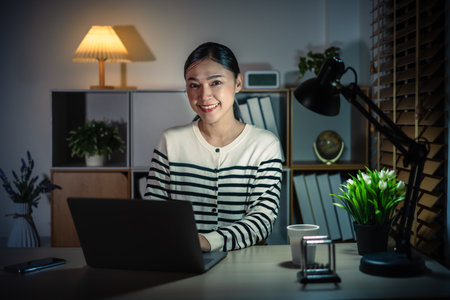 happy woman working with laptop at a nightの写真素材