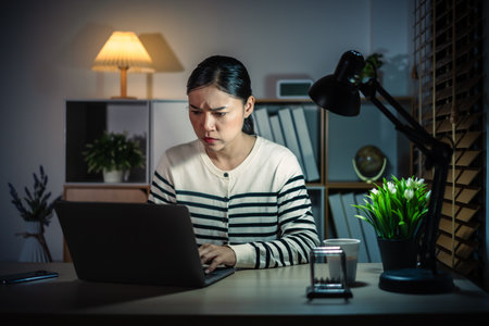 stressed woman working with laptop at a nightの写真素材