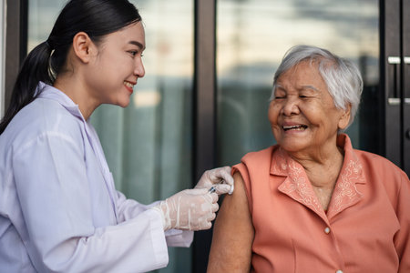 doctor holding syringe and making injection a vaccine to happy senior womanの写真素材