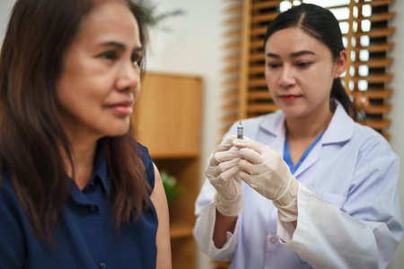 doctor holding syringe and making injection vaccine to female patientの写真素材