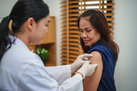 doctor holding syringe and making injection vaccine to female patientの写真素材