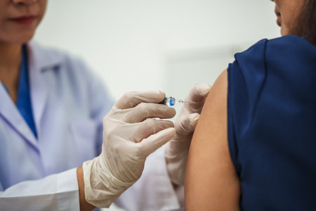 doctor holding syringe and making injection vaccine to female patientの写真素材