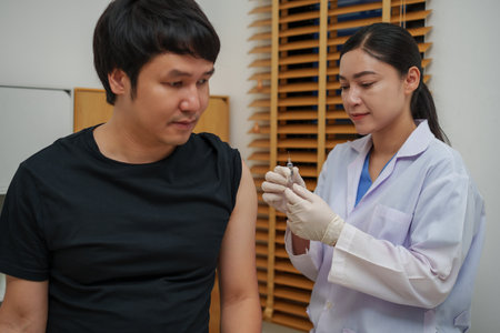 doctor holding syringe and making injection vaccine to male patientの写真素材