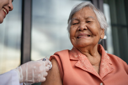 doctor holding syringe and making injection a vaccine to happy senior womanの写真素材