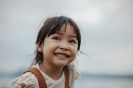 happy toddler girl smiling on a grass field near the riverの写真素材