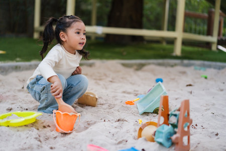 happy child girl playing sand with toy on the playgroundの写真素材