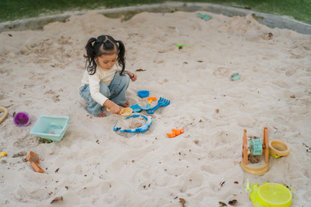 happy child girl playing sand with toy on the playgroundの写真素材