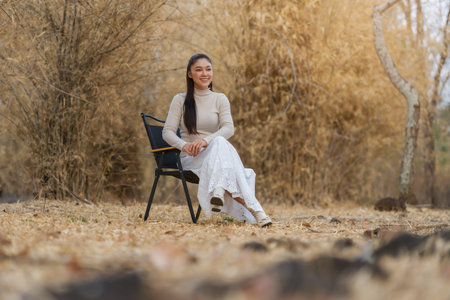 Young woman relaxing on a chair in a quiet natural setting in a dry forestの写真素材