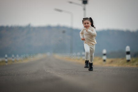 Energetic little child girl running happily on an open roadの写真素材