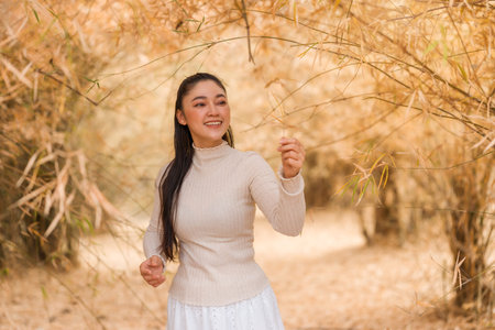 Young woman enjoying the peaceful atmosphere of a golden bamboo forest.の写真素材
