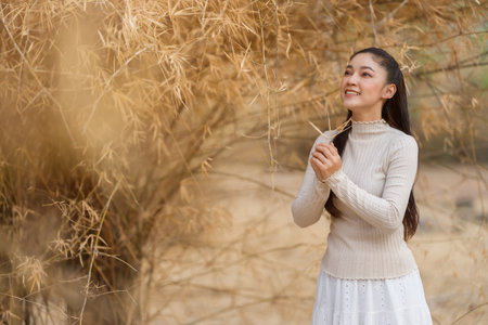 Beautiful young woman posing among dry bamboo branches forest in nature.の写真素材