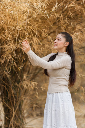 Beautiful young woman posing among dry bamboo branches forest in nature.の写真素材