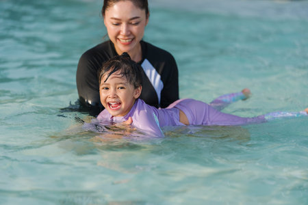 preschool child girl playing and swimming with her mother in the pool