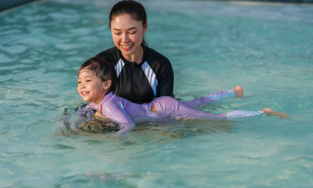 preschool child girl playing and swimming with her mother in the pool