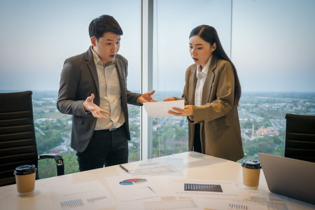 Shocked two business colleagues looking at bad results on paper with surprised expression in...