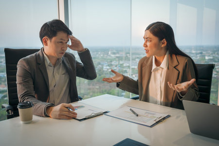 two business partners meeting and looking at documents with stressed and confused expressions in modern officeの写真素材